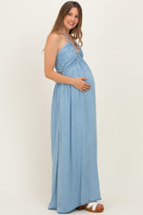 woman wearing a light blue maternity maxi dress with a gathered bodice and holding her baby bump