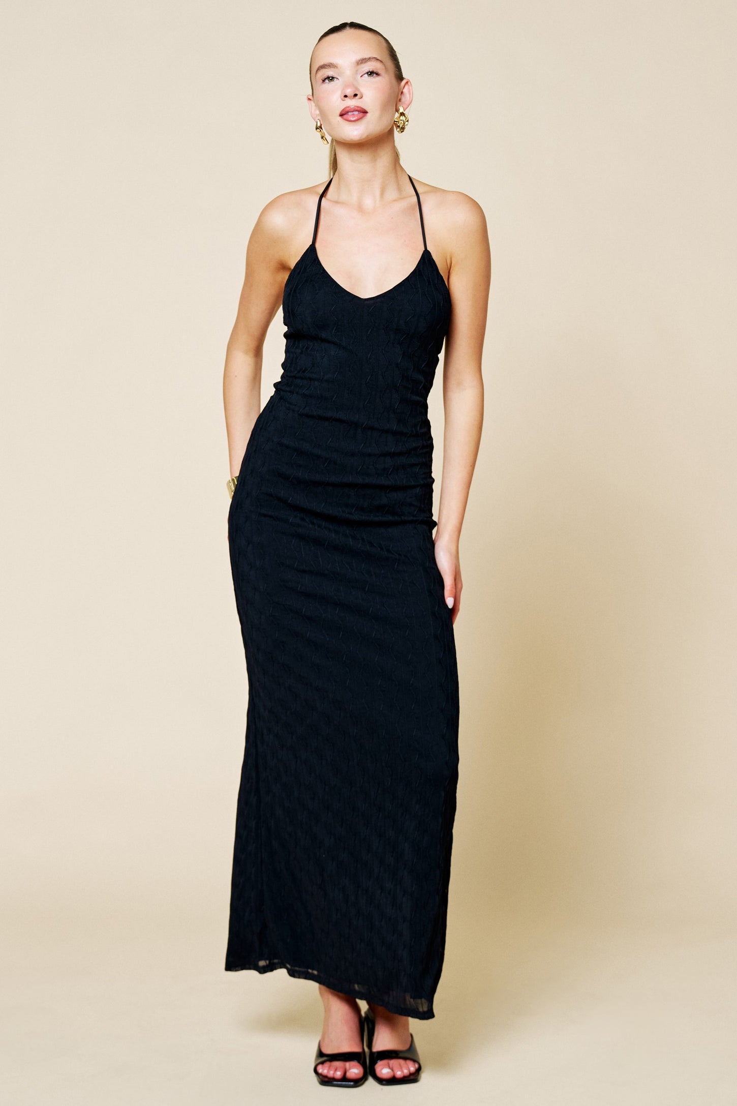 woman wearing a black sleeveless maxi dress with a fitted silhouette and adjustable spaghetti straps