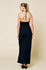woman wearing a backless black maxi dress with a halter neck and textured fabric