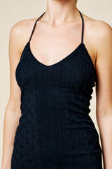 woman wearing a black knitted spaghetti strap dress with a v-neckline and textured wavy pattern