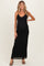 woman wearing a black maternity maxi dress with a v-neck and spaghetti straps, gently accentuating her baby bump