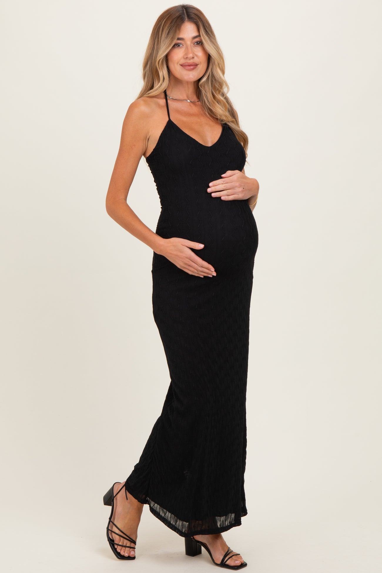 woman wearing a black maternity maxi dress with a fitted silhouette and holding her baby bump