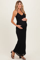 woman wearing a black maternity maxi dress with a fitted silhouette and holding her baby bump