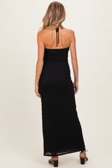 woman wearing a black maternity maxi dress with a halter neck and back ruching, showing her baby bump