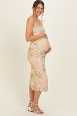 woman wearing a blush floral strapless maternity dress, showcasing her baby bump with a fitted silhouette