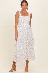 woman wearing a white floral midi dress with adjustable straps and a fitted bodice