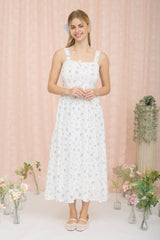 woman wearing a white floral midi dress with adjustable straps and a smocked bodice, standing in a decorated setting