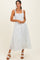 woman wearing a white midi dress with blue floral print and square neckline, standing with hands clasped