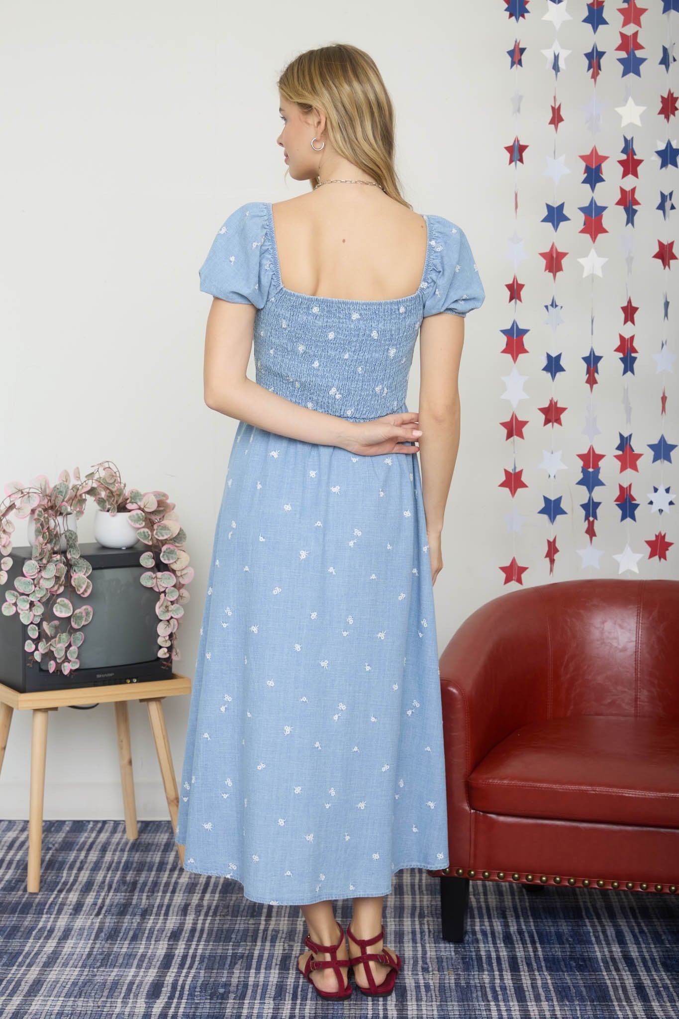 woman wearing a blue cotton midi dress with puff sleeves and a smocked back, featuring white floral patterns