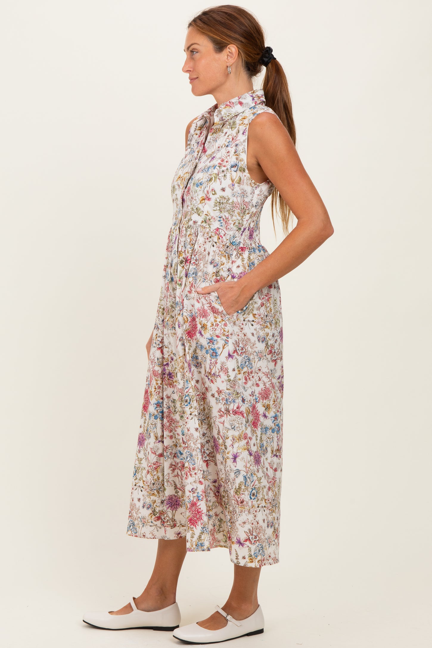 woman wearing a sleeveless floral print midi dress with a collar and pockets