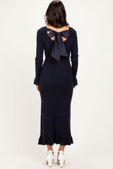 woman wearing a navy blue ribbed long sleeve dress with a back bow detail and ruffled hemline