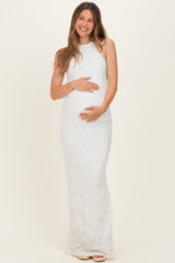 woman wearing a white sleeveless maternity gown with textured detailing, holding her baby bump
