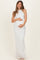 woman wearing a white sleeveless maternity gown with textured detailing, holding her baby bump