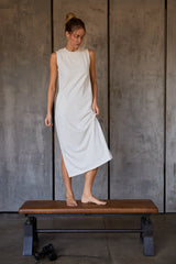 woman wearing a gray sleeveless midi dress standing on a bench with a relaxed pose