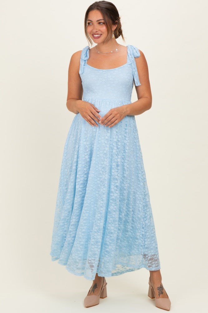 woman wearing a light blue lace maternity dress with tie straps and a flowing skirt, showing a baby bump