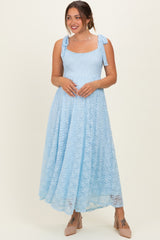 woman wearing a light blue lace maternity dress with tie straps and a flowing skirt, showing a baby bump