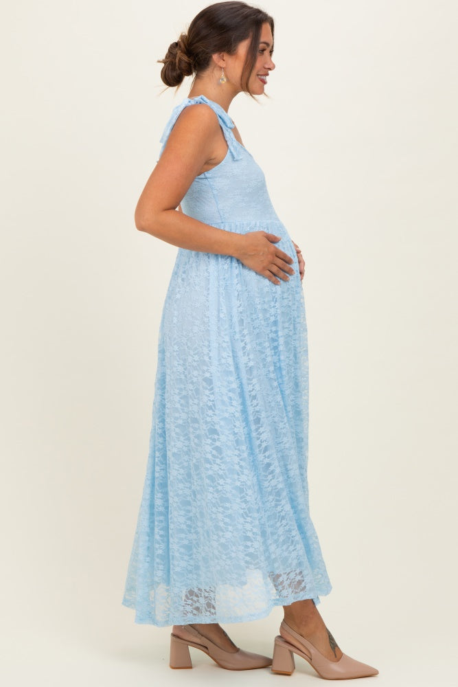 woman wearing a light blue lace maternity maxi dress, gently cradling her baby bump, with a side profile view