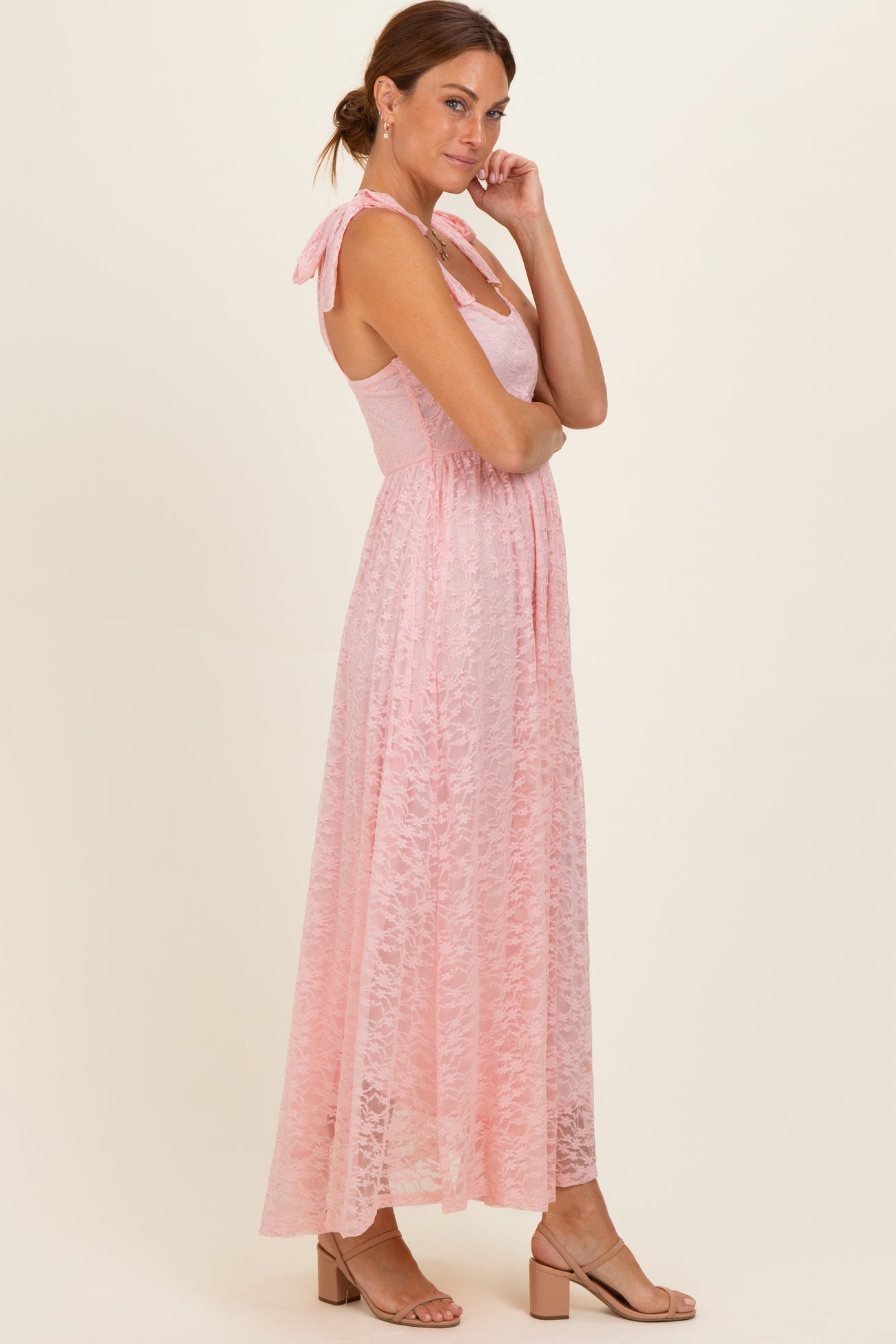 woman wearing a pink lace maxi dress with tie straps and a fitted bodice