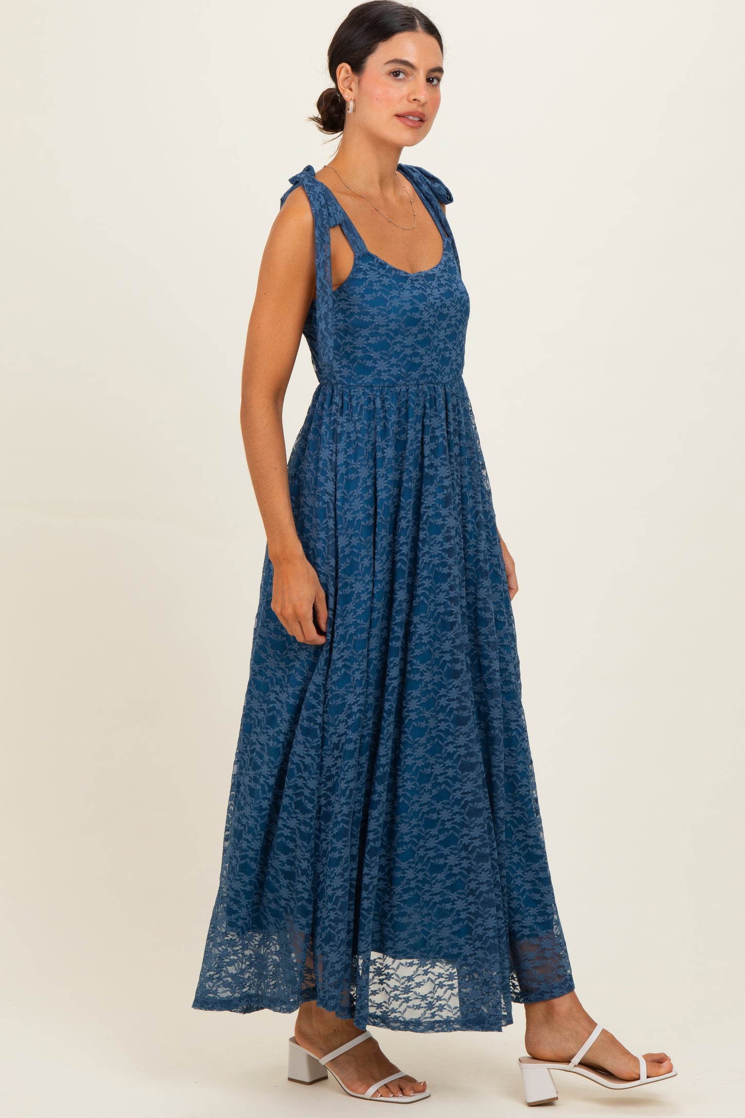 woman wearing a blue lace maxi dress with tie shoulder straps and a flowing skirt