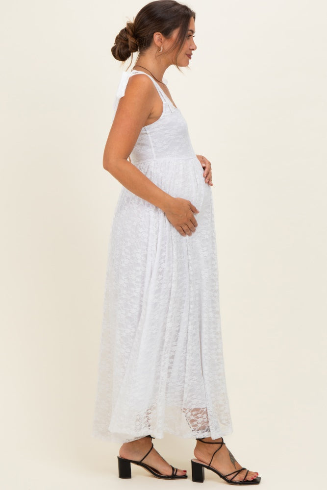 woman wearing a white lace maternity maxi dress and holding her baby bump