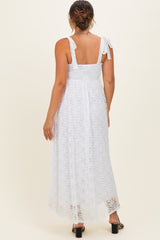 woman wearing a white lace maternity maxi dress with tie straps, showing the back view and a flowing silhouette