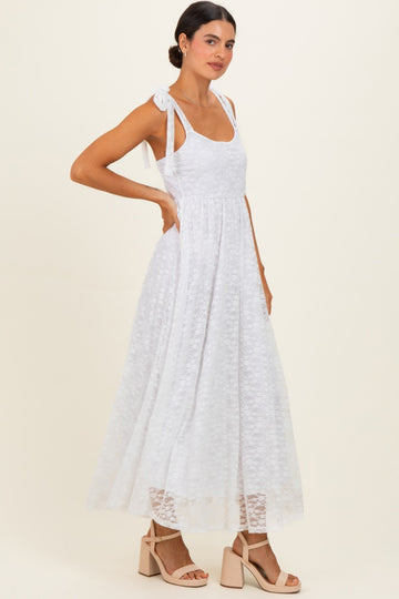 woman wearing a white lace maxi dress with tie shoulder straps and a flowy skirt