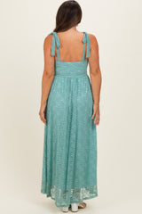 woman wearing a light teal maternity maxi dress with back tie straps and a flowing lace design