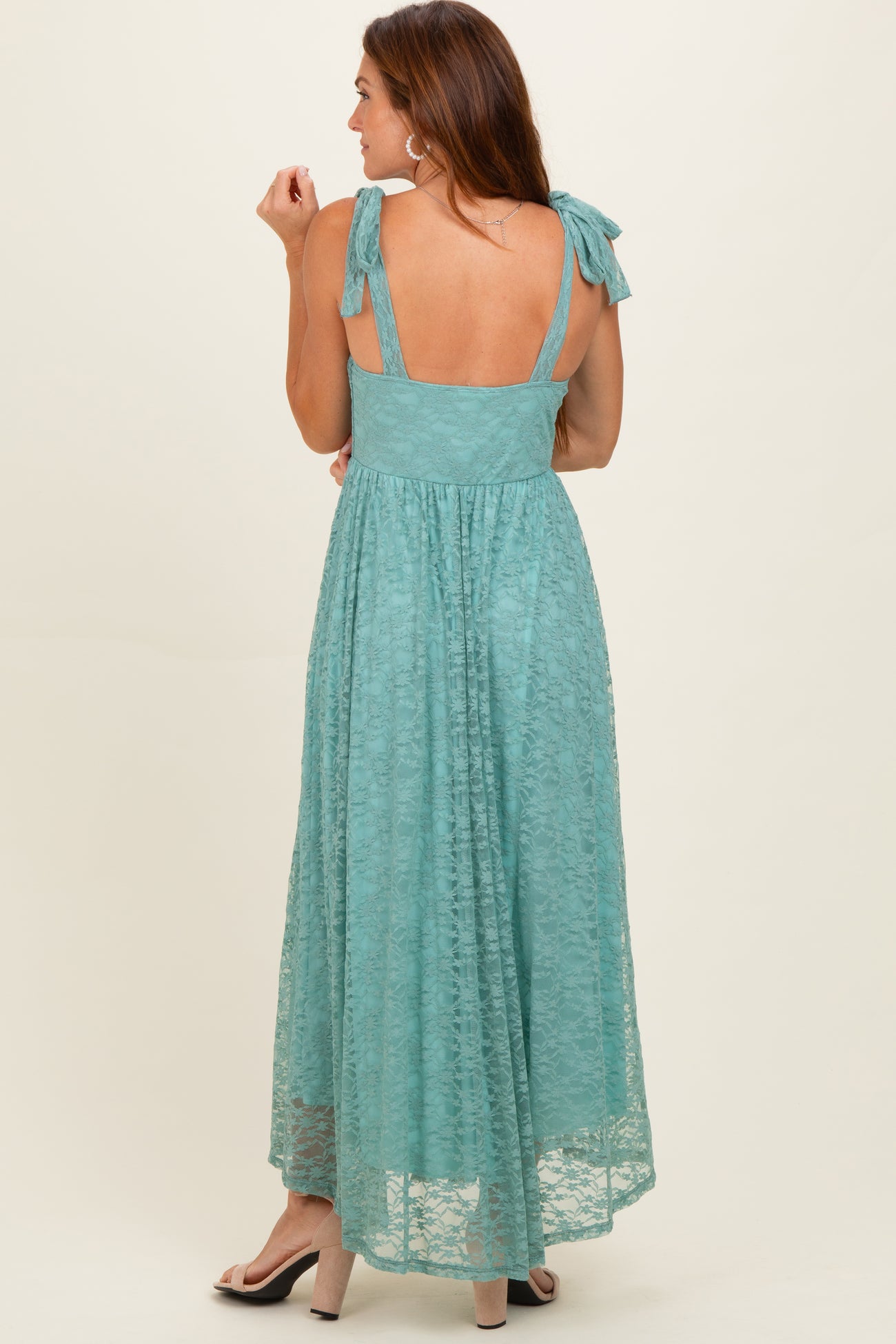 woman wearing a teal back-tying maxi dress with lace detailing and a flowy skirt