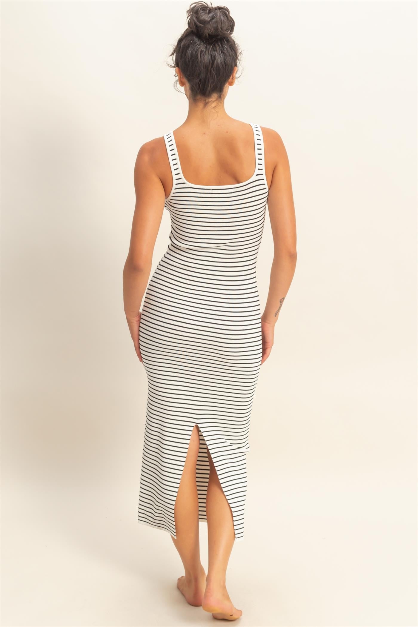 woman wearing a black and white striped maxi dress with a side slit and a square neckline