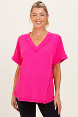 woman wearing a bright pink v-neck maternity top with rolled short sleeves and a relaxed fit