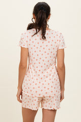 woman wearing a light pink short sleeve top and matching shorts with a floral pattern from the back