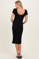 woman wearing a black short sleeve ribbed maternity dress, showing the back view