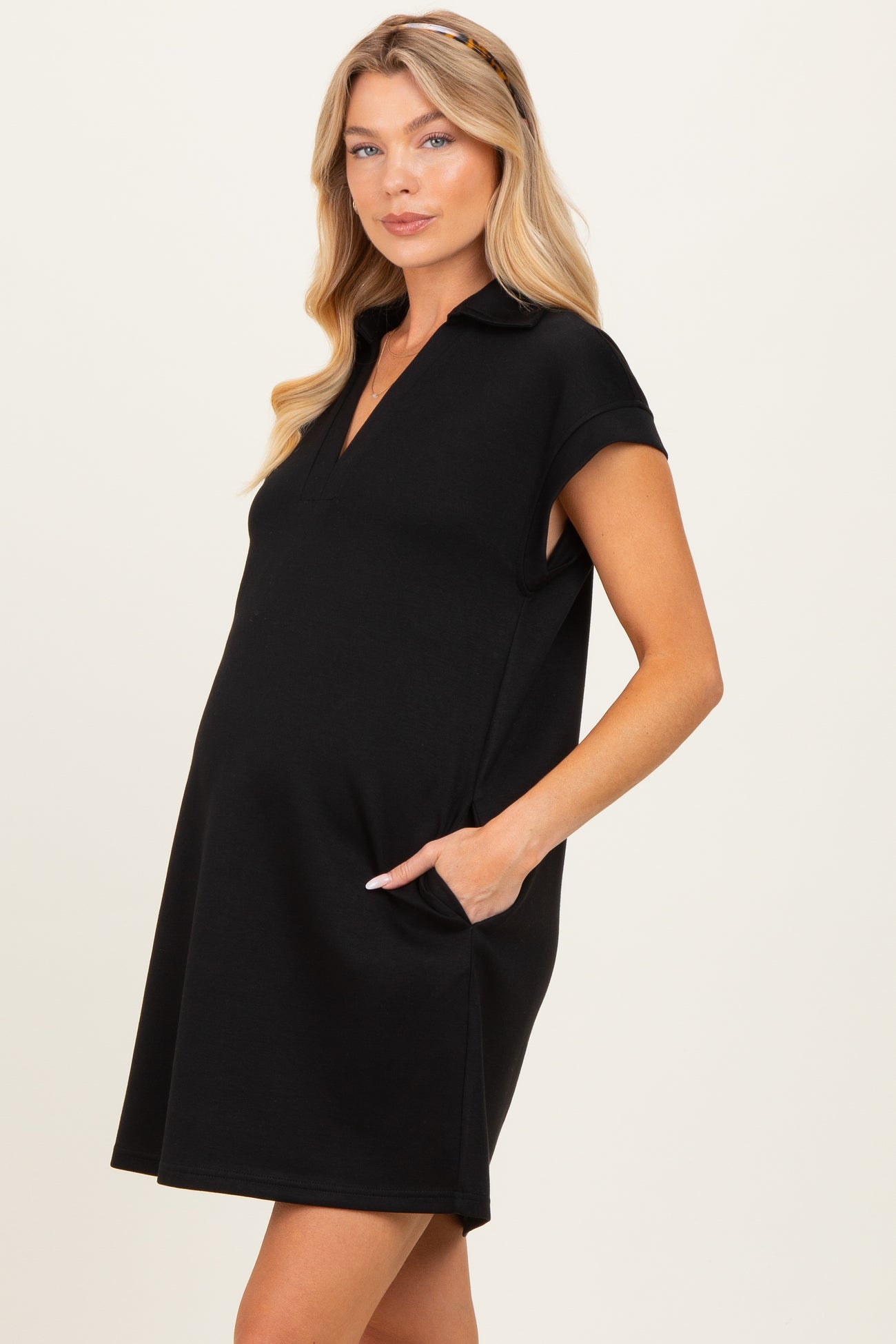 woman wearing a black maternity polo dress with pockets and a visible baby bump