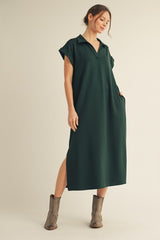 woman wearing a dark green short sleeve collared maxi dress with side pockets and slit, paired with gray ankle boots