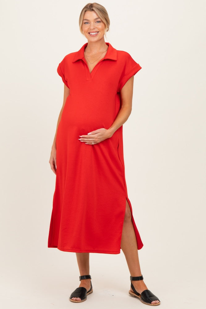 woman wearing a red maternity dress with a collared neckline and side slits, smiling and holding her baby bump