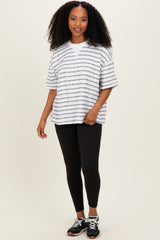 woman wearing a striped oversized gray and white t-shirt with black leggings and sneakers