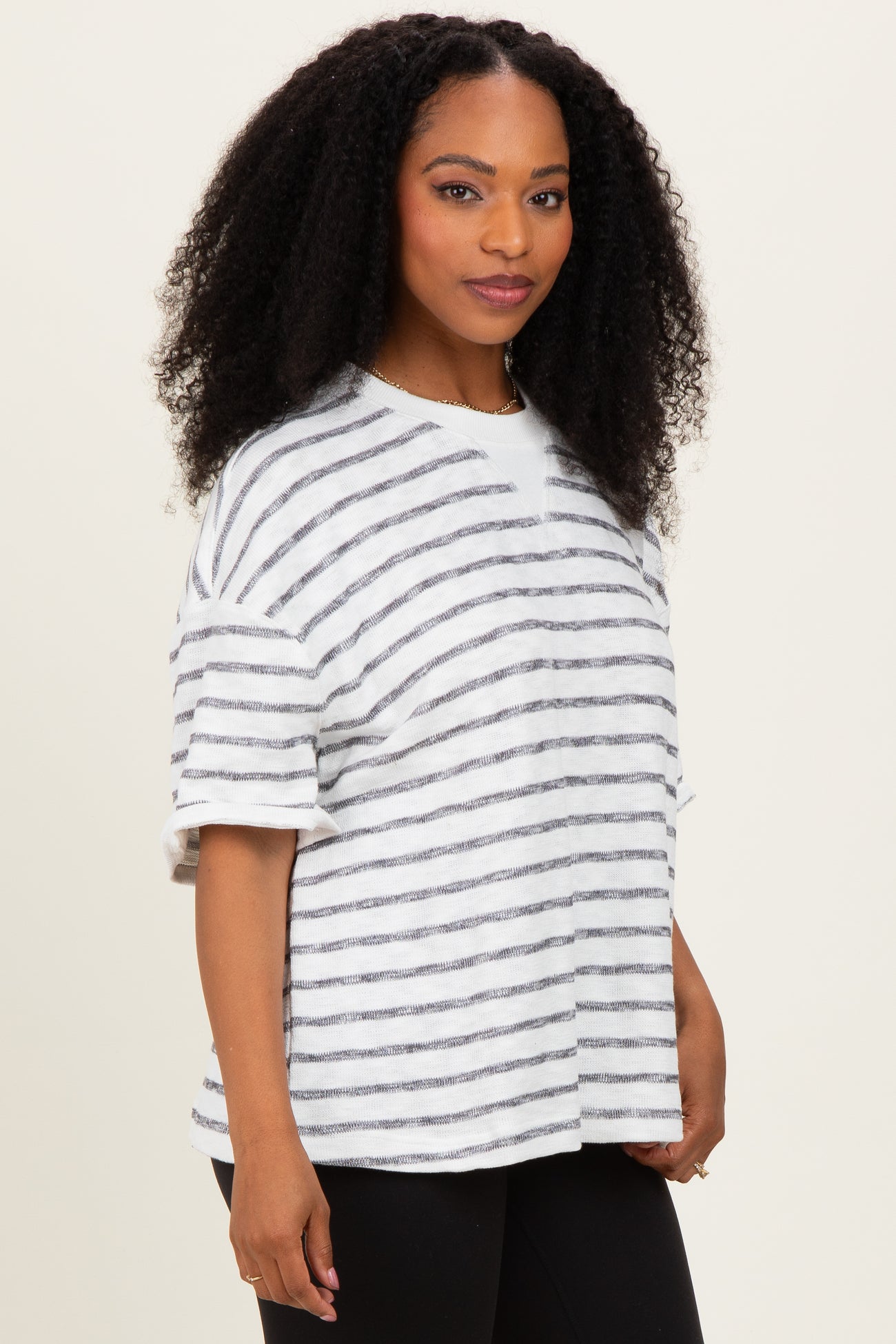 woman wearing a white and gray striped oversized t-shirt with rolled sleeves and a relaxed fit