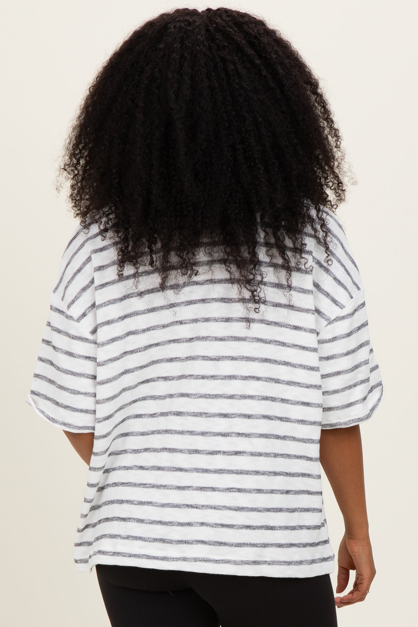 woman wearing a white and gray striped oversized t-shirt, viewed from the back