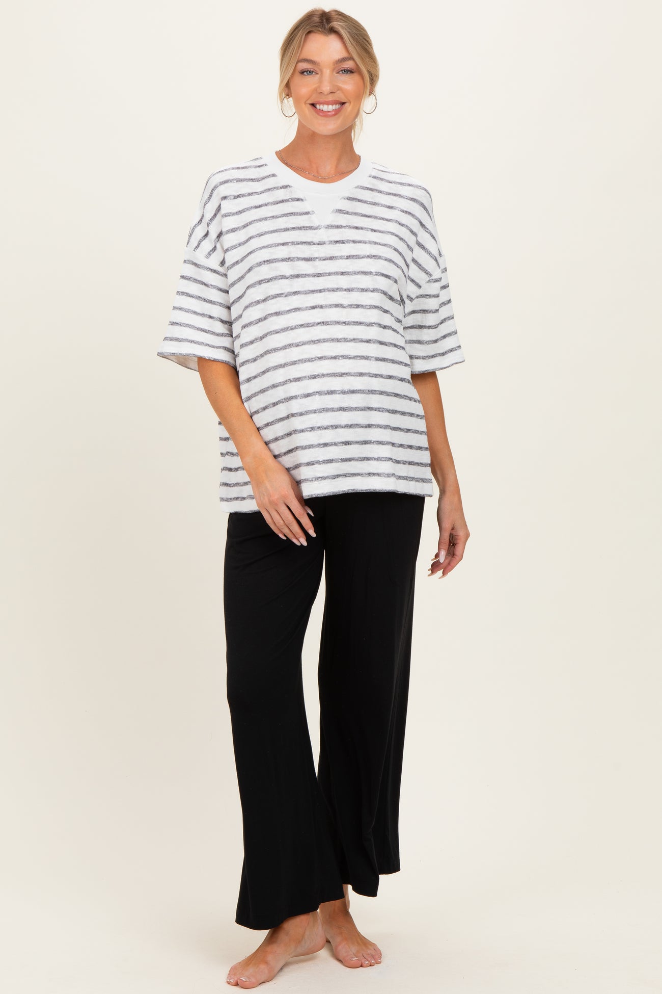 woman wearing a striped maternity top and black lounge pants, showcasing a baby bump