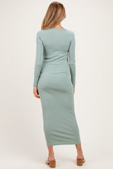 woman wearing a light green long sleeve maternity dress, showing a fitted silhouette from the back