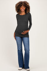 woman wearing a dark gray long sleeve maternity top and blue flared jeans, showcasing her baby bump