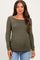 woman wearing an olive green long sleeve maternity top with side ruching and a visible baby bump