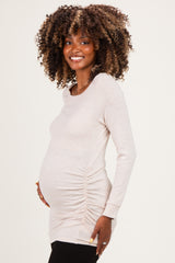 woman wearing a light beige long sleeve maternity top with side ruching and a visible baby bump