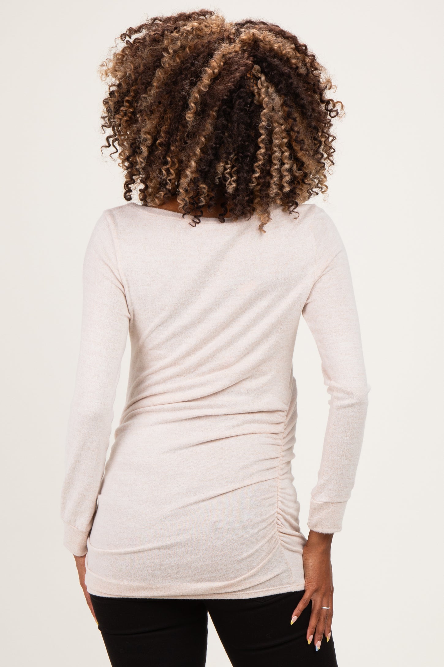 woman wearing a light pink long sleeve maternity top with ruching at the sides, viewed from the back