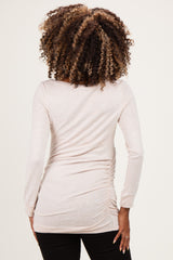 woman wearing a light pink long sleeve maternity top with ruching at the sides, viewed from the back