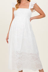 woman wearing a white maternity dress with ruffled straps and embroidered details, featuring a fitted bodice and flowy skirt