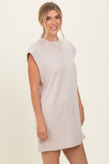 woman wearing a light beige sleeveless dress with a relaxed fit and shoulder detailing