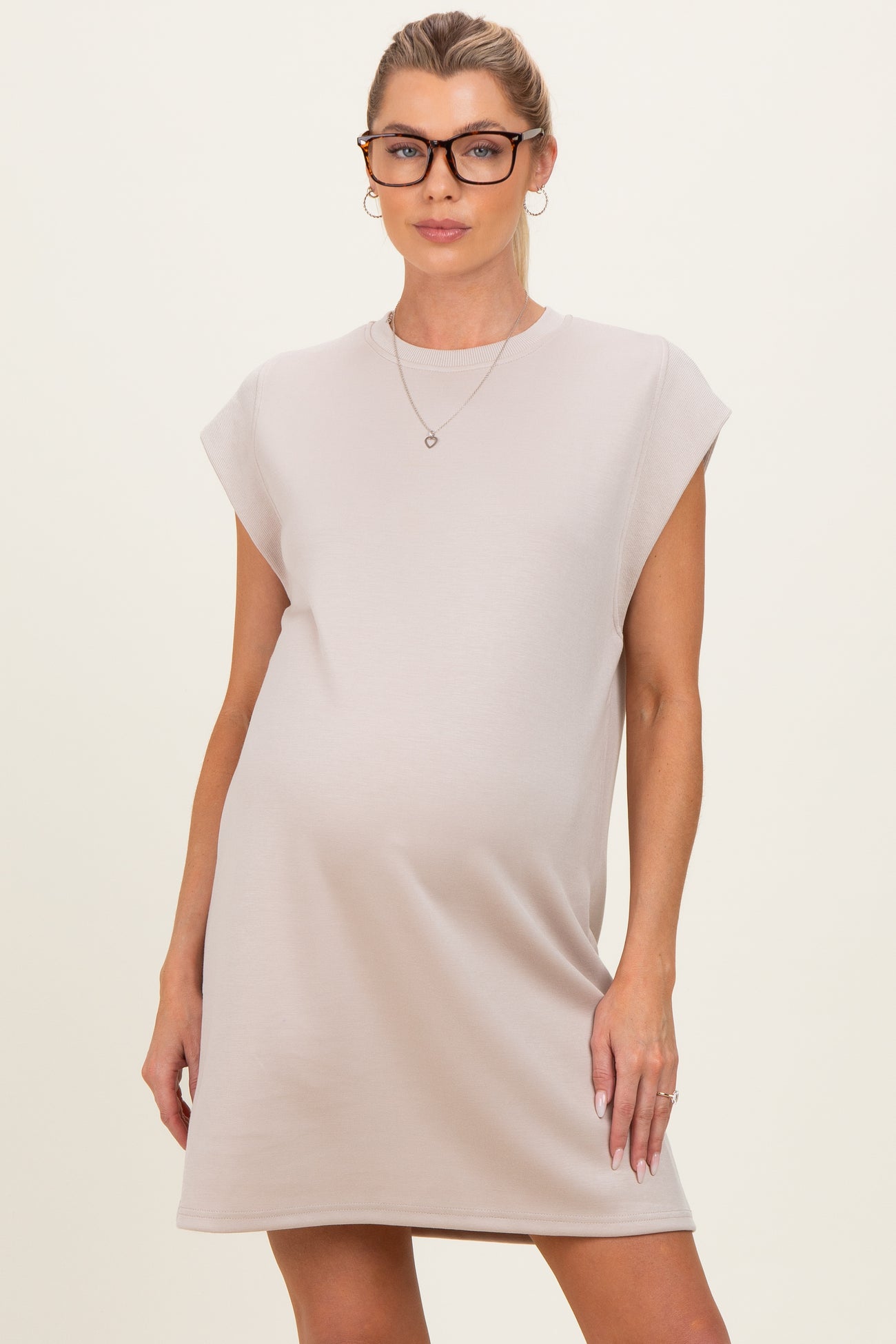 woman wearing a beige maternity dress with cap sleeves and a relaxed fit, showcasing a baby bump