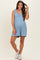 woman wearing a light blue maternity romper with ruffle straps and a relaxed fit, showing her baby bump