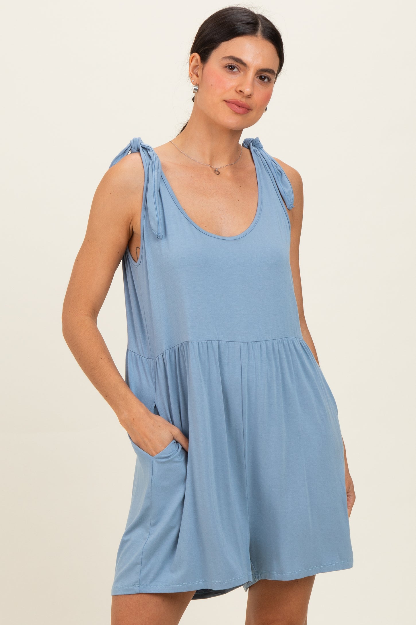 woman wearing a light blue sleeveless romper with tie straps and side pockets